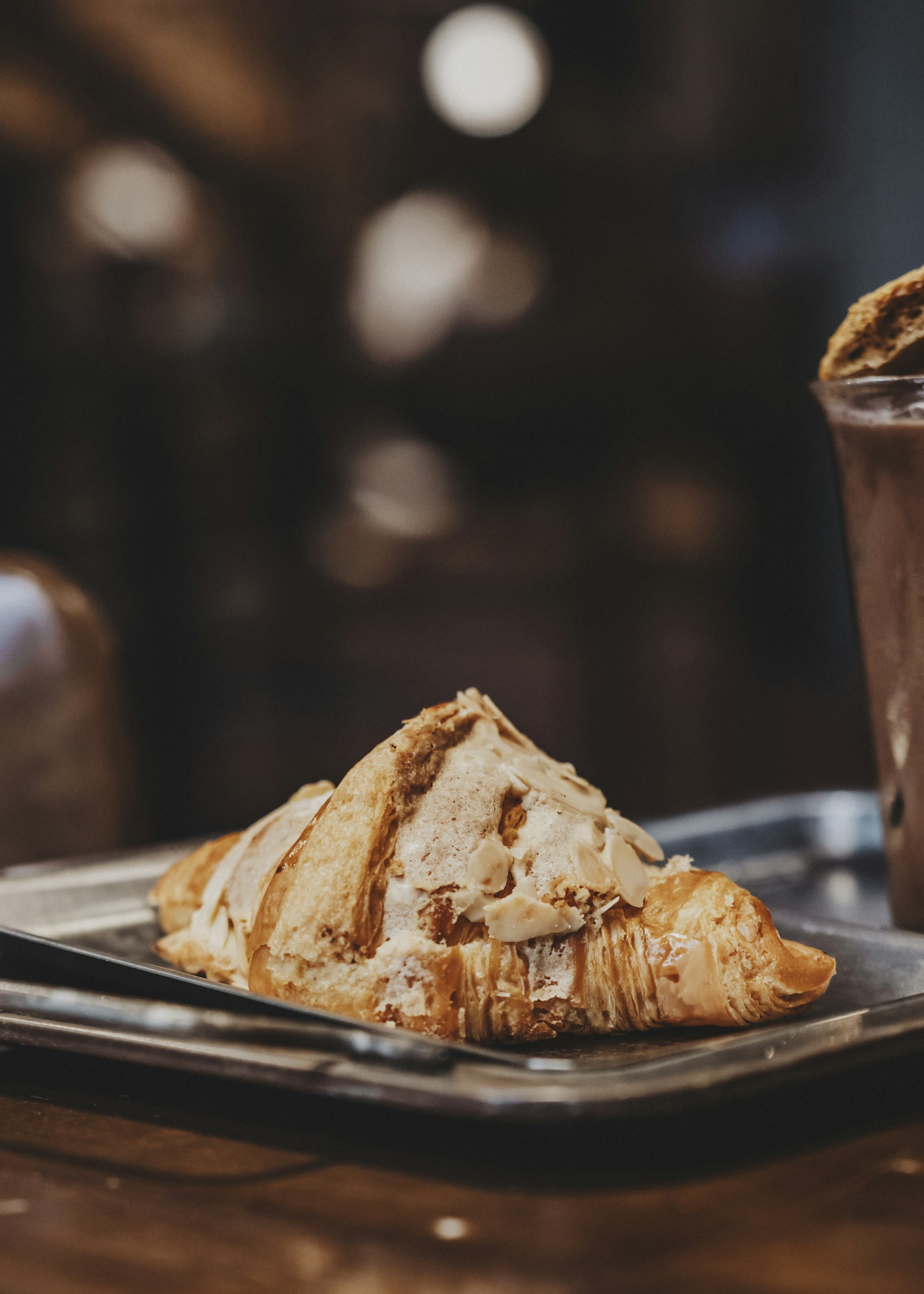 A croissant topped with pale cream on a cafe tray