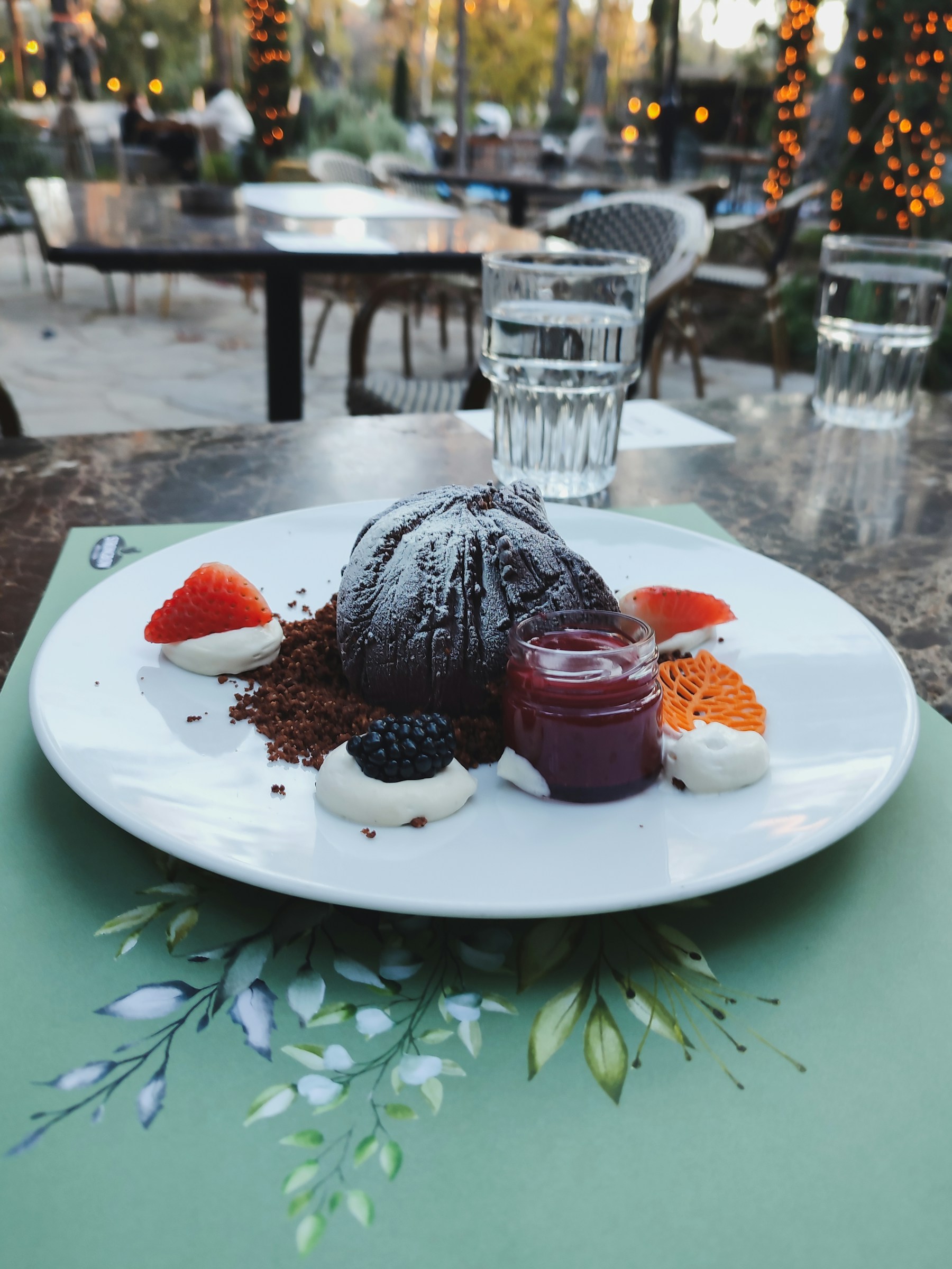 A plated chocolate lava cake with berries, jam and cream